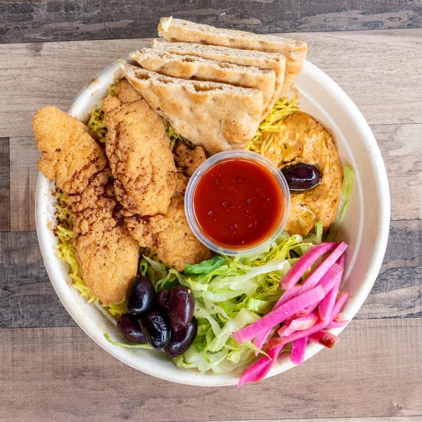 A bowl of chicken tenders, yellow rice, pita bread, hummus, olives, lettuce, pickled turnips, and red sauce.